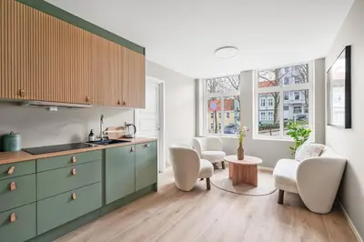 a kitchen with green cabinets and two chairs and a table at BRAND NEW! Bergen Beds Apartments I Cozy Corner in Bergen