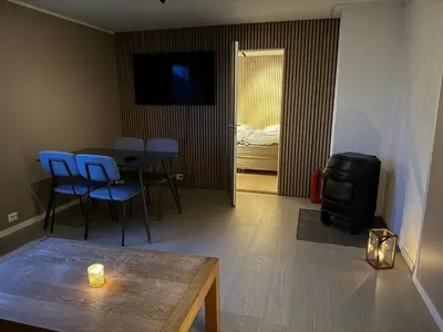 a living room with a table and chairs and a television at Leilighet på Harøya in Ålesund