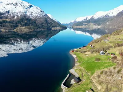 an aerial view of a lake with snow covered mountains at Flo Lake House in Stryn