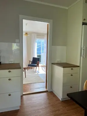 a kitchen with white cabinets and a door leading to a living room at Flo Lake House in Stryn