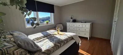 a bedroom with a bed and a dresser and a window at Home in Sylta
