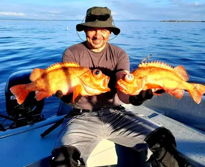 a man holding two large fish in a boat at Home in Sylta