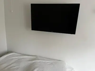 a flat screen tv hanging on a wall next to a bed at Leilighet i Lillehammer med gratis parkering in Lillehammer