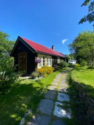 a small house with a red roof and a stone path at Lite hus i hagen in Malvik