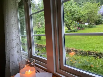a candle sitting on a table in front of a window at Lite hus i hagen in Malvik