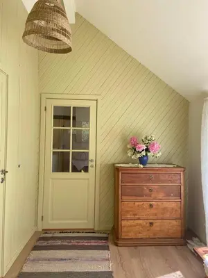 a room with a door and a dresser with flowers on it at Lite hus i hagen in Malvik