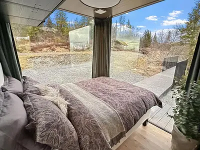 a bed in a room with a large window at Spegill Escape to Mirror Glass and Breathtaking Calm at 1000m in Aurdal