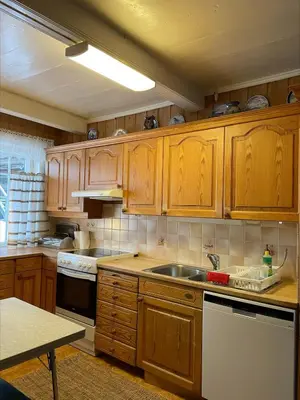 a kitchen with wooden cabinets and a sink at Koselig tømmerhus på gammel gård i Skåbu in Graupe