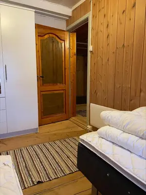 a room with a bed and a door and a rug at Koselig tømmerhus på gammel gård i Skåbu in Graupe