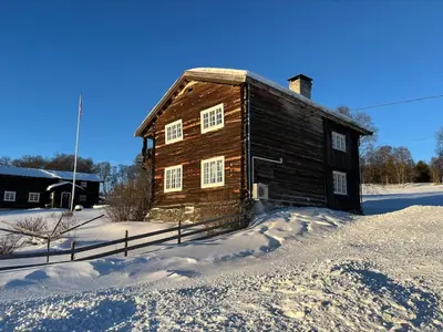 a wooden building in the snow with a fence at Koselig tømmerhus på gammel gård i Skåbu in Graupe