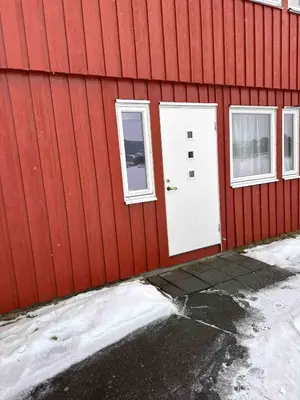 a red building with two windows and a white door at Small apartment in Meldal in Syrstad