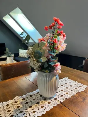 a white vase with flowers on a wooden table at The Jugend Loft in Ålesund