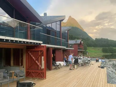 a group of people standing outside of a building with a mountain at Near-Sea Boat House With Panoramic Views in Sykkylven