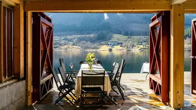 a table and chairs on a porch with a view of a lake at Near-Sea Boat House With Panoramic Views in Sykkylven