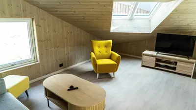 a living room with a yellow chair and a television at Near-Sea Boat House With Panoramic Views in Sykkylven
