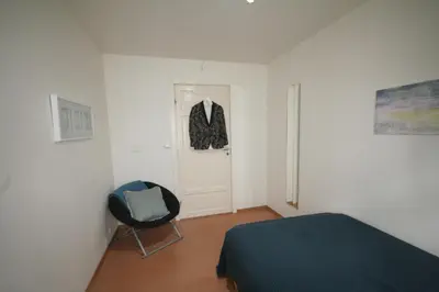 a bedroom with a bed and a suit hanging on a door at Super cozy 3-bedroom in picturesque neigborhood in Bergen