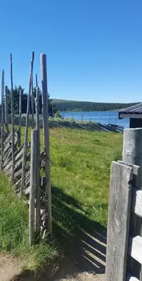 a wooden fence in a field with a body of water at Cabin Lillehammer, Nordseter, Sjusjøen in Lillehammer