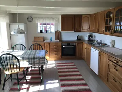 a kitchen with wooden cabinets and a table and a table and chairs at Gamlemgarden by Norgesbooking - house by the sea in Longva