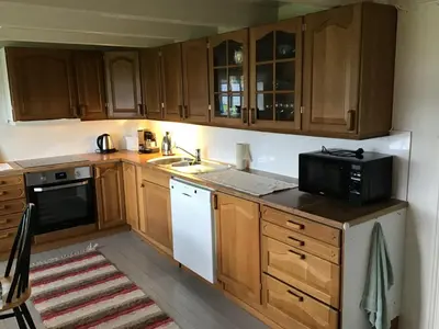 a kitchen with wooden cabinets and a microwave at Gamlemgarden by Norgesbooking - house by the sea in Longva