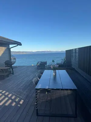 a picnic table on a deck with a view of the water at Large villa with boathouse in Lunde