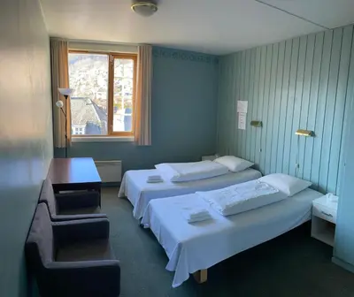 a hotel room with two beds and a chair at Ole Bull Akademiet in Vossevangen