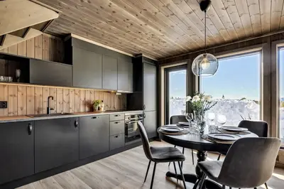 a kitchen with a table and chairs and a dining room at New, cozy cottage on Norefjell with stunning views in Noresund