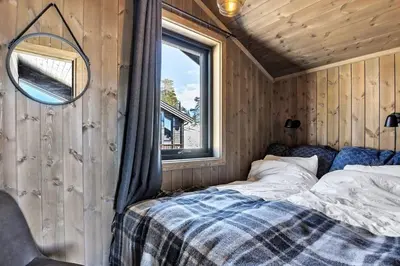 a bed in a room with a mirror and a window at New, cozy cottage on Norefjell with stunning views in Noresund
