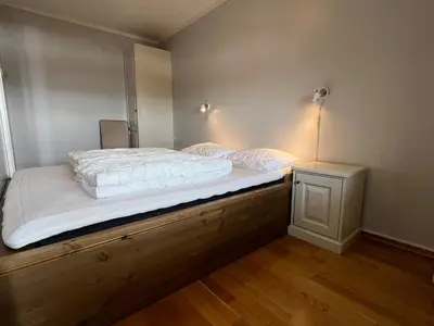 a bedroom with a bed with white sheets and a night stand at Appartment at Stølstunet in Beitostølen in Beitostøl