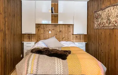 a bedroom with a bed with wooden walls and white cabinets at Gorgeous Home In Bjorli With Wifi in Bjorli