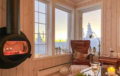 a living room with a fireplace in a room with windows at Beautiful Home In Sjusjøen With Wifi in Sjusjøen