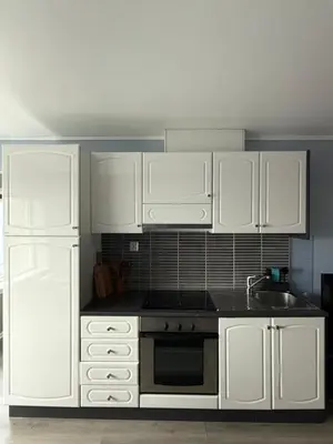 a kitchen with white cabinets and a sink and a refrigerator at Apartment by the center of Ålesund in Ålesund