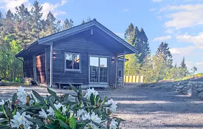 a small cabin with white flowers in front of it at Awesome Home In Sletta With Wifi in Sletta