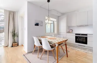 a white kitchen with a wooden table and white chairs at 2 bedroom, lake view, light rail, Bergen in Bergen