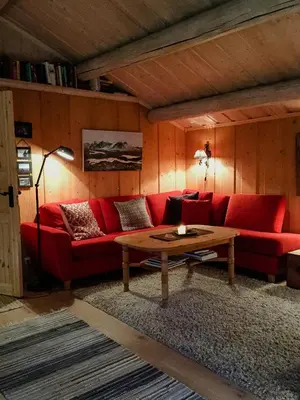 a living room with a red couch and a table at Modern Log Cabin By Hardangervidda in Dagali