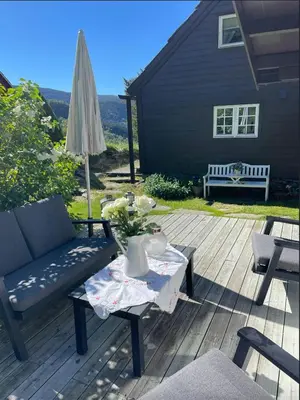 a patio with a couch and a table and an umbrella at Historic Farm With Sea View Over Bjørnefjorden