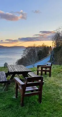 a group of picnic tables on a field with a lake at Historic Farm With Sea View Over Bjørnefjorden