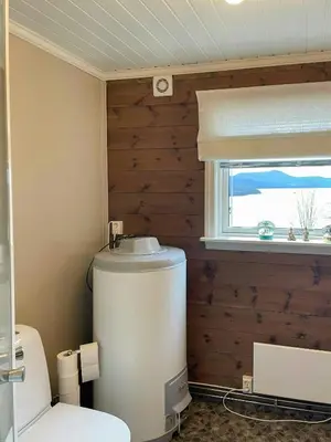 a bathroom with a toilet and a window at Historic Farm With Sea View Over Bjørnefjorden