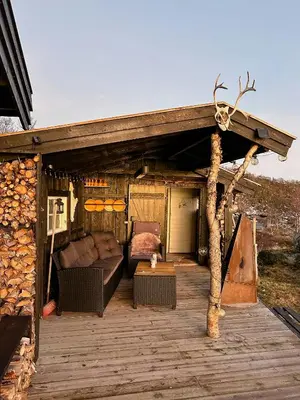 a wooden deck with a couch and a table at Idyllic Cabin By The Water In Hessdalen in Ålen