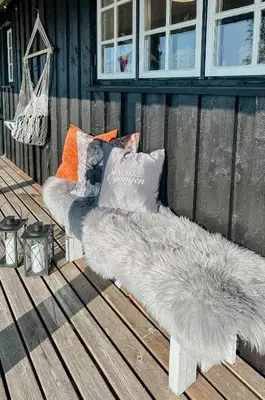 a white bench with pillows on a deck at Idyllic Cabin By The Water In Hessdalen in Ålen