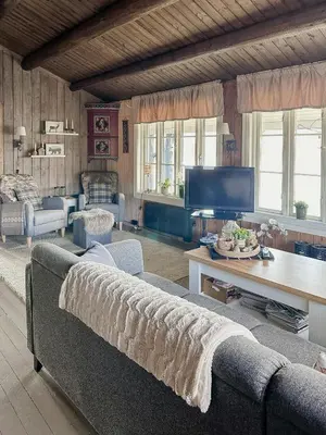 a living room with a couch and a tv at Idyllic Cabin By The Water In Hessdalen in Ålen