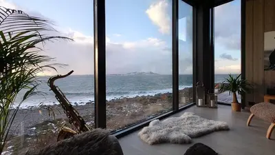 a room with a view of the ocean from a room with windows at Coastal Cabin With Ocean View On Lepsøya in Kjerstad