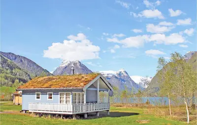 a house with a grass roof with mountains in the background at Stunning Home In Fjærland in Fjarland