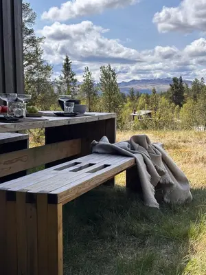 a wooden bench sitting in the grass with a blanket on it at Large and family friendly cabin near Langedrag in Tunhovd