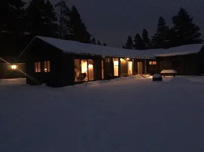 a house in the snow at night with lights at Large and family friendly cabin near Langedrag in Tunhovd