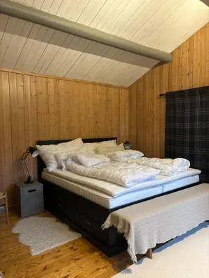 a large bed in a room with wooden walls at Large and family friendly cabin near Langedrag in Tunhovd