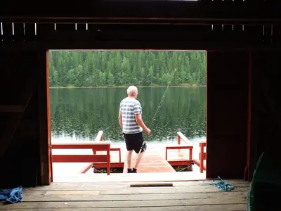 a man standing on a dock on a lake at Gravraakstuggu in Storneve