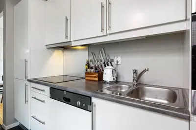 a kitchen with white cabinets and a sink at Bright City Apartment - Perfect Central Stay in Bergen