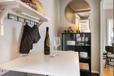 a white kitchen with a wine bottle and glasses at Bright City Apartment - Perfect Central Stay in Bergen