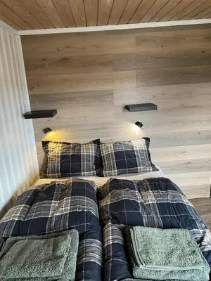 a bed in a room with a wooden wall at Golsfjellet in Gol