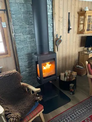 a wood stove with a fire in a room at Golsfjellet in Gol